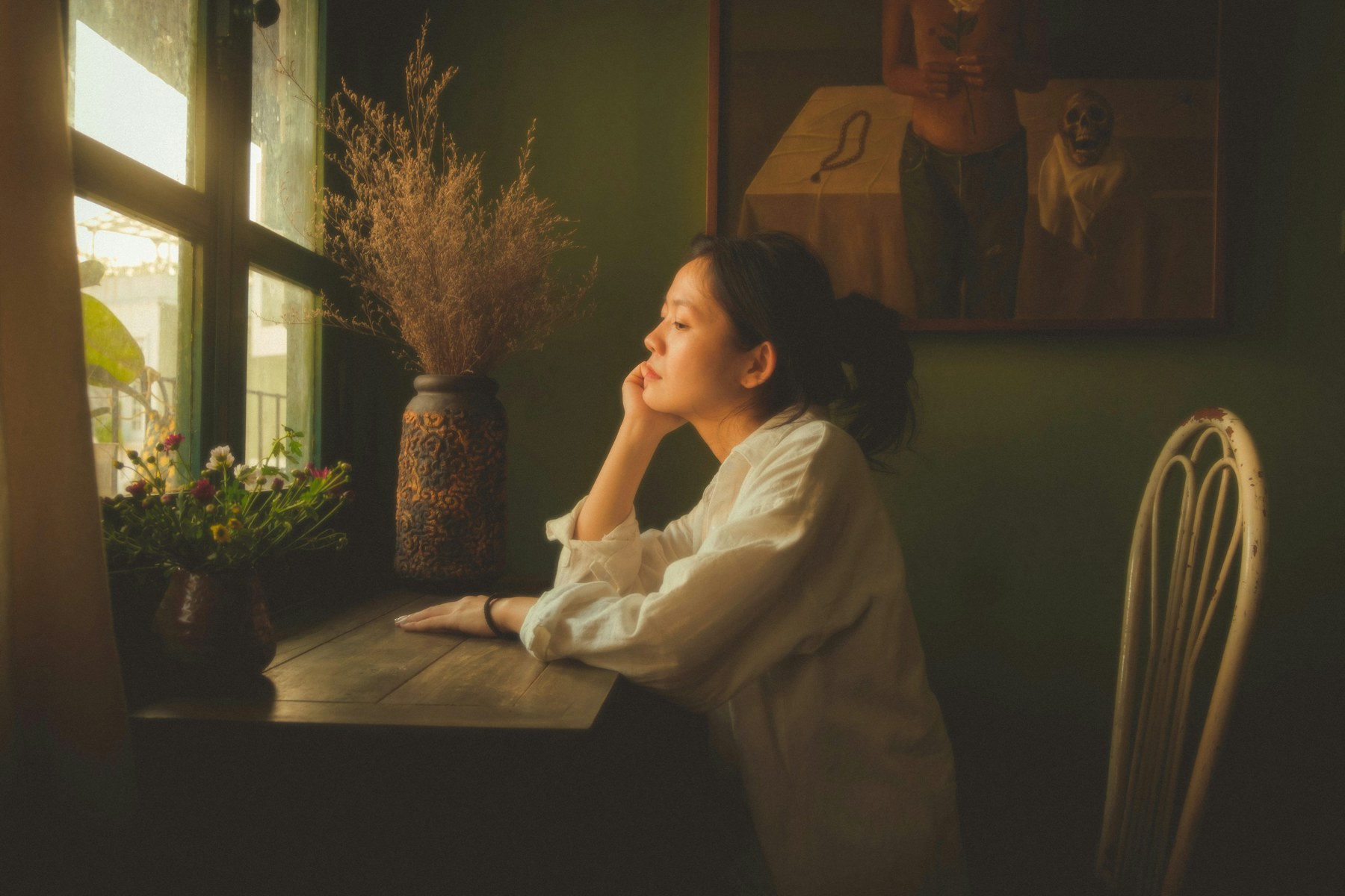A woman sitting quietly beside a window