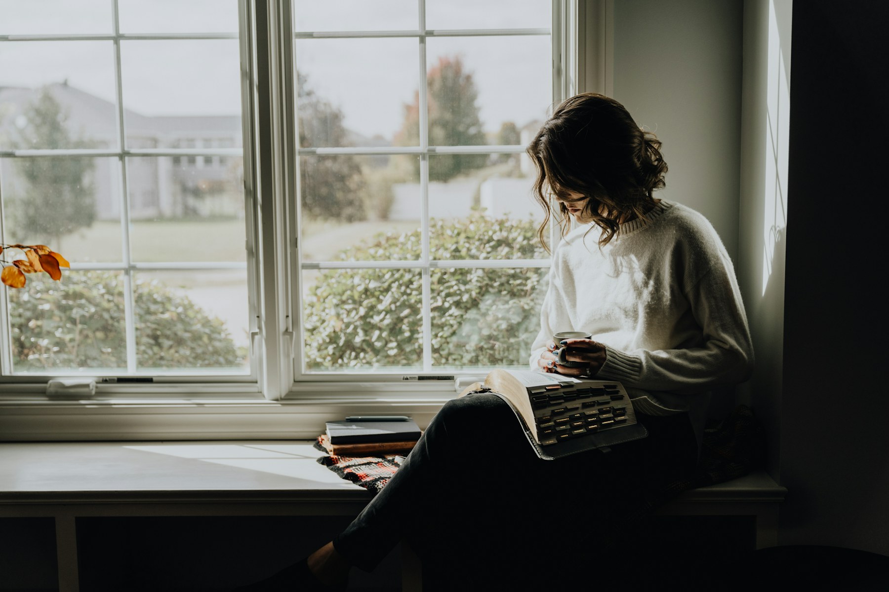 A woman reading at home with a warm drink