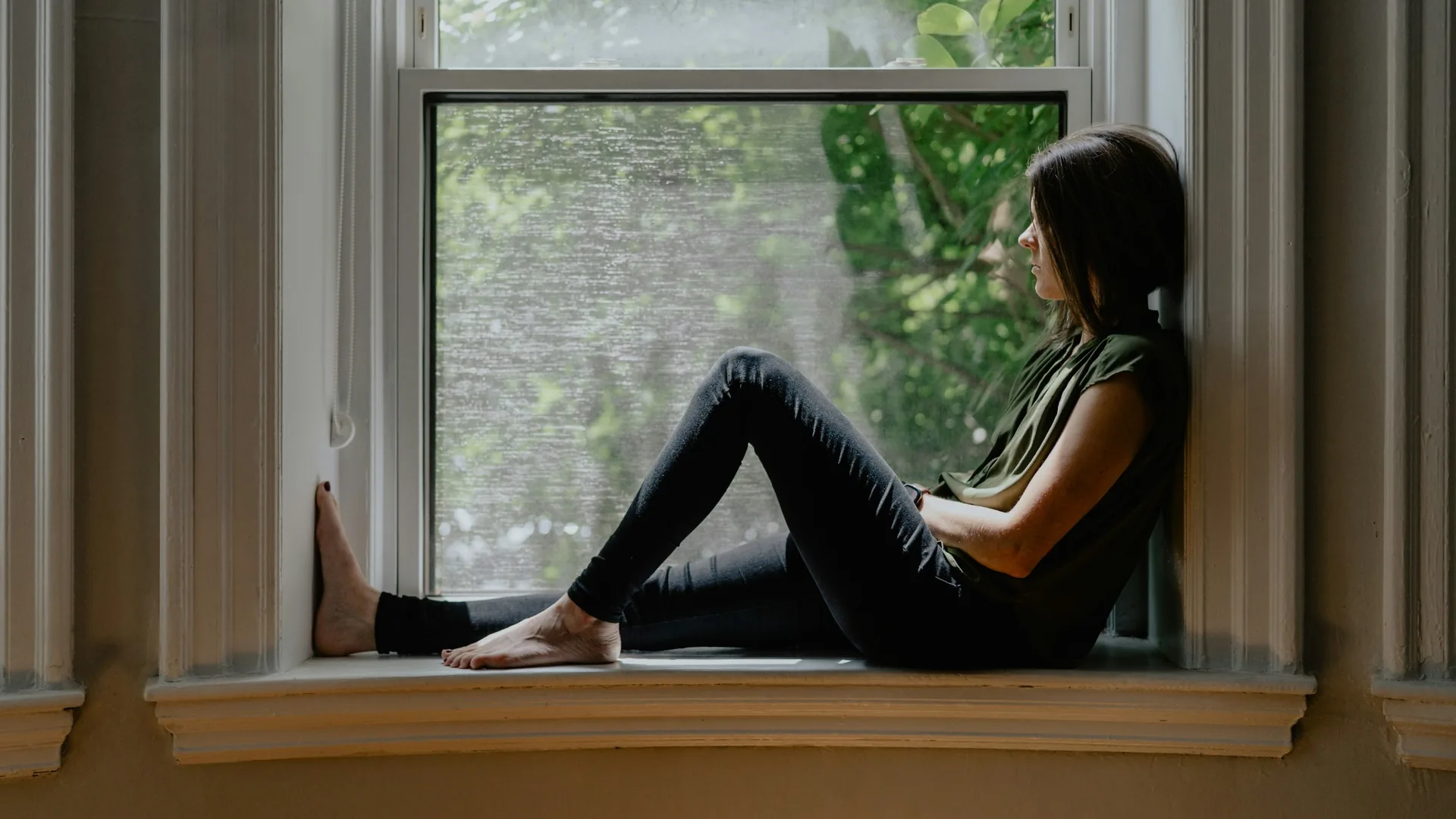 A woman sitting quietly beside a window